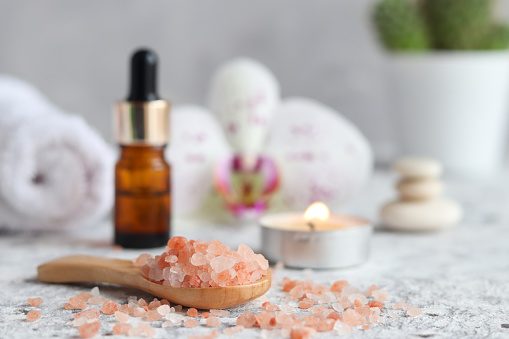 Massage set with pink himalayan salt, essential oil, scented candle, orchid flower, zen stones and towel. Beauty and spa concept. Selective focus.